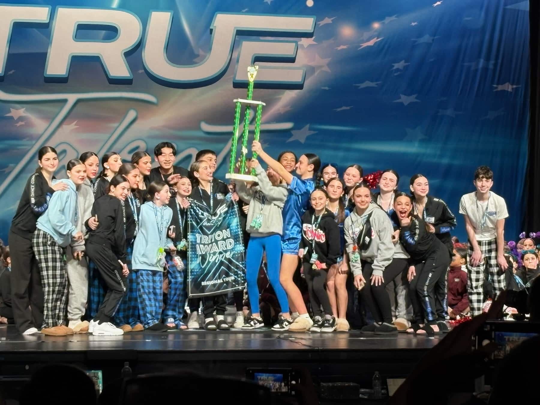 Icon dancers celebrating with a True Talent award on stage.